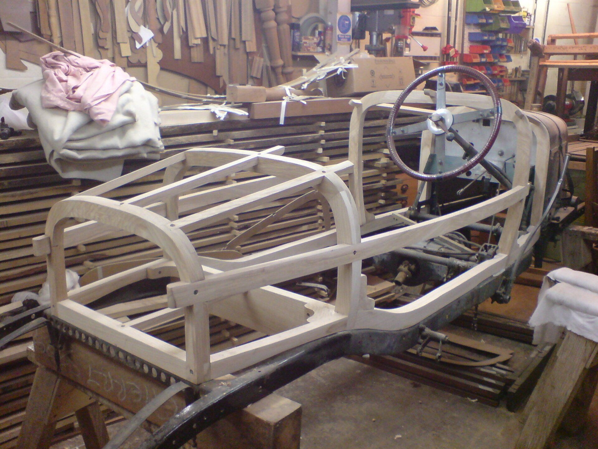 A wooden car frame with a steering wheel in a workshop