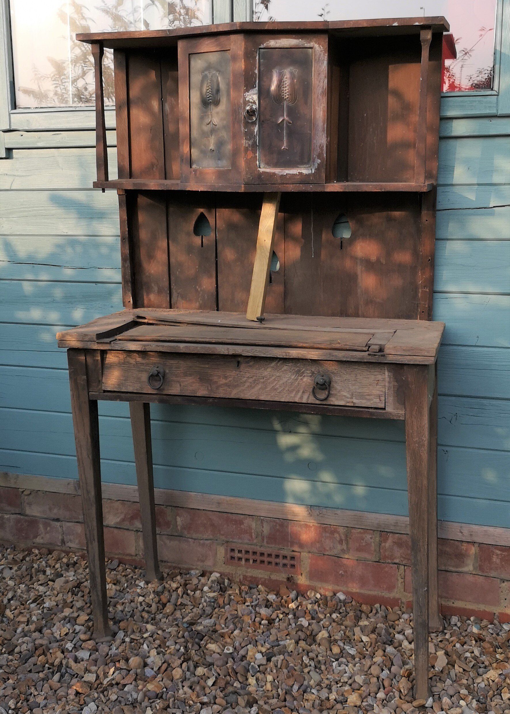 An old wooden desk is sitting in front of a blue wall