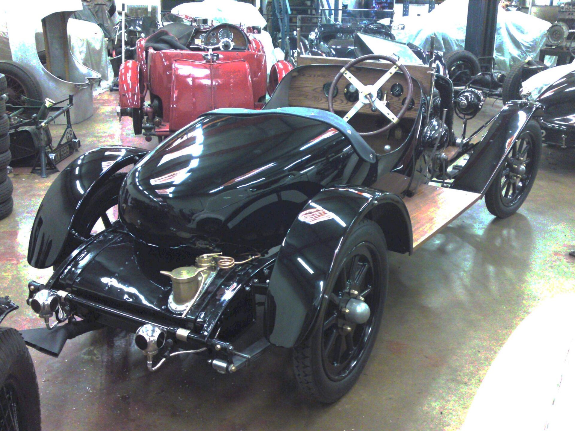 A black car with a steering wheel sits in a garage