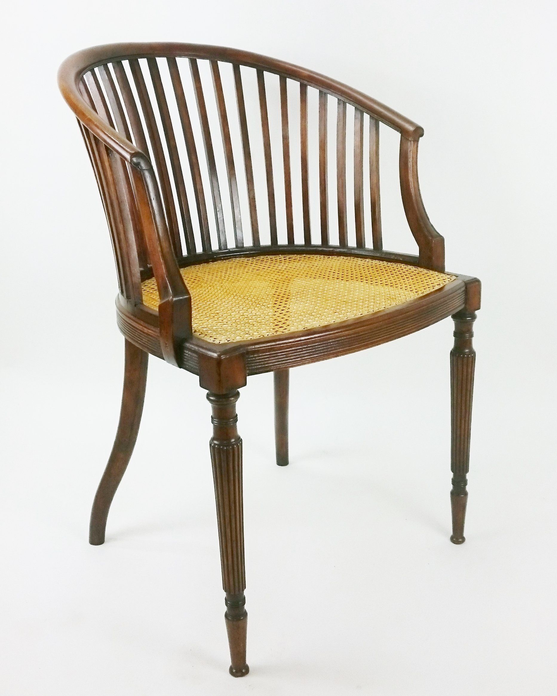 A wooden chair with a wicker seat sits on a white surface