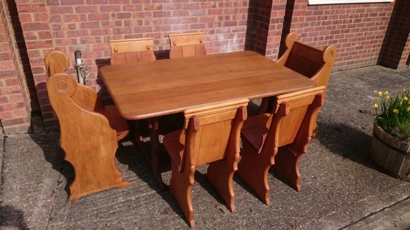 A wooden table and chairs are sitting on a sidewalk in front of a brick building.