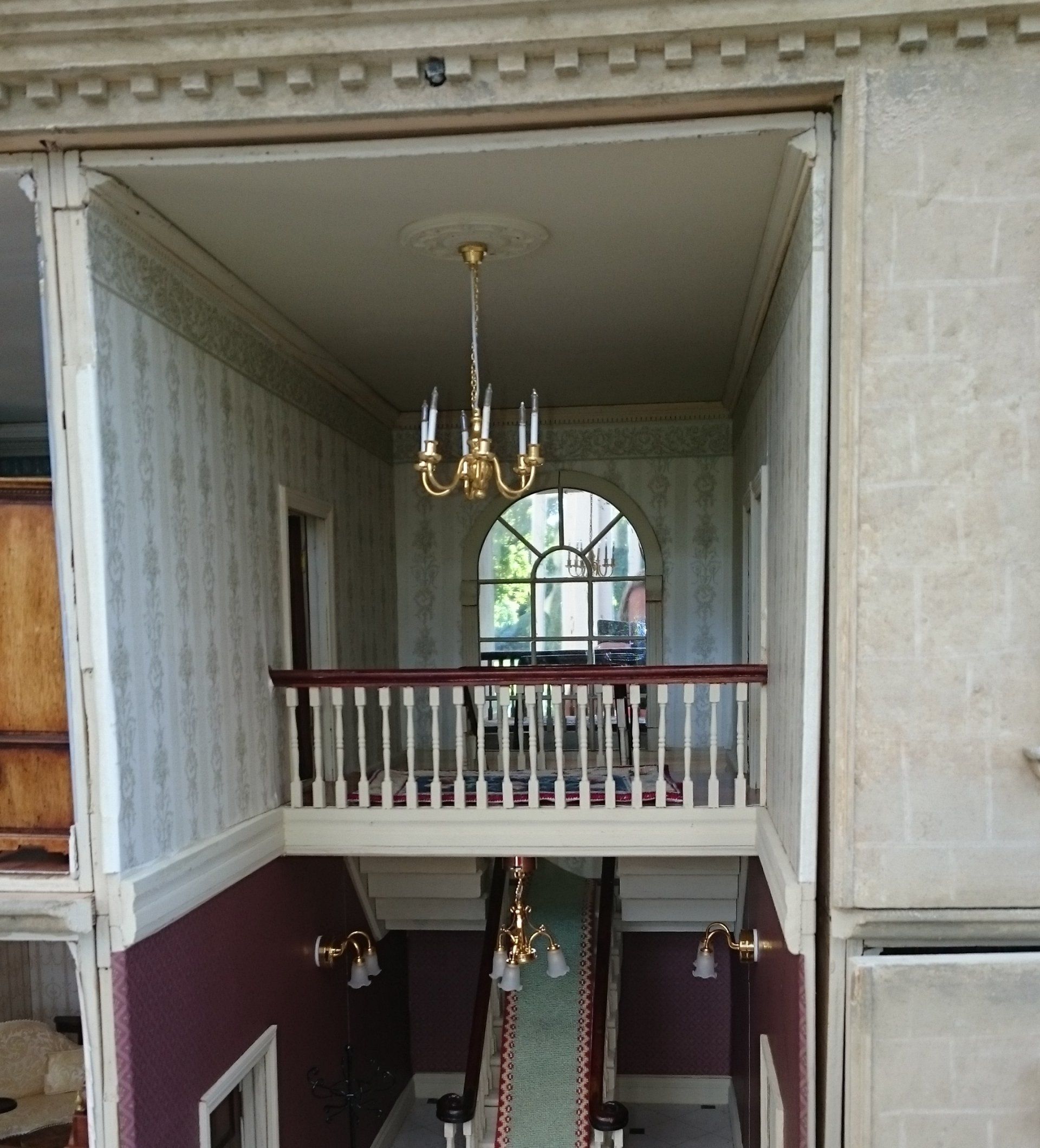 A doll house with a balcony and stairs