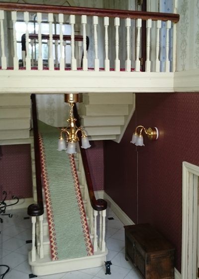 A staircase with a green carpet and a white railing