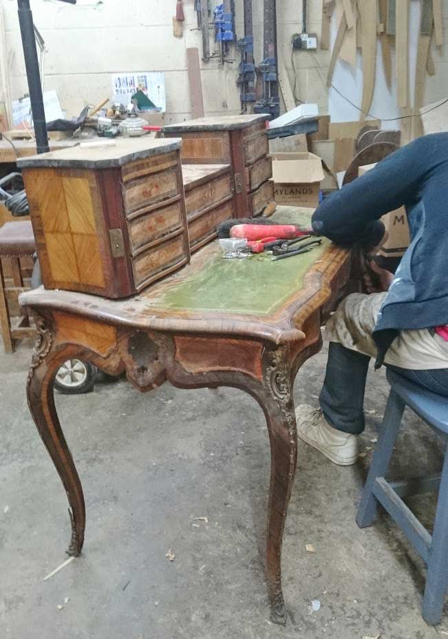 A person is sitting at a wooden table in a workshop.