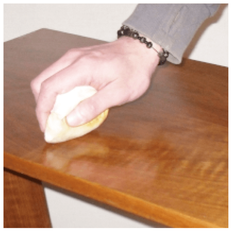 A person wearing a bracelet is polishing a wooden table