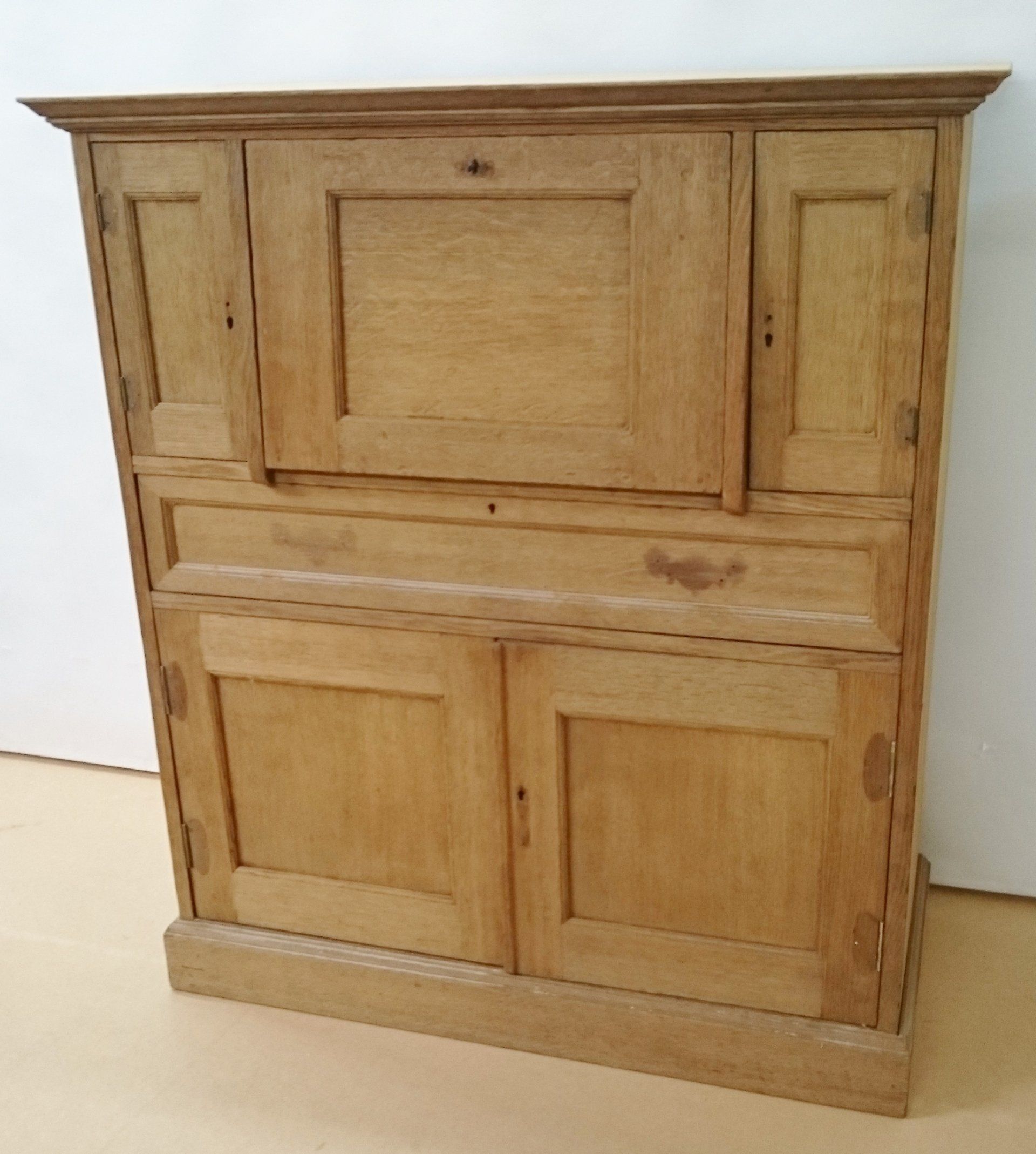 A wooden cabinet with drawers and doors is sitting on a wooden floor