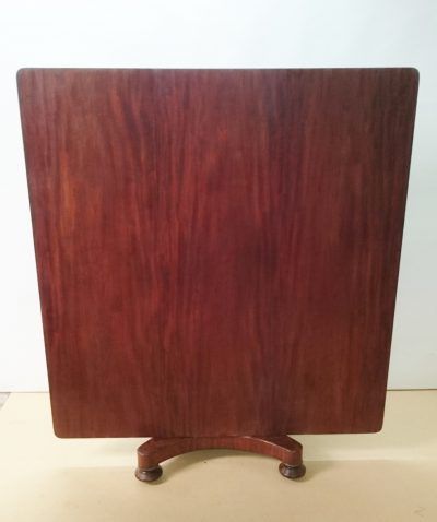 A wooden table with wheels is sitting on a wooden floor.