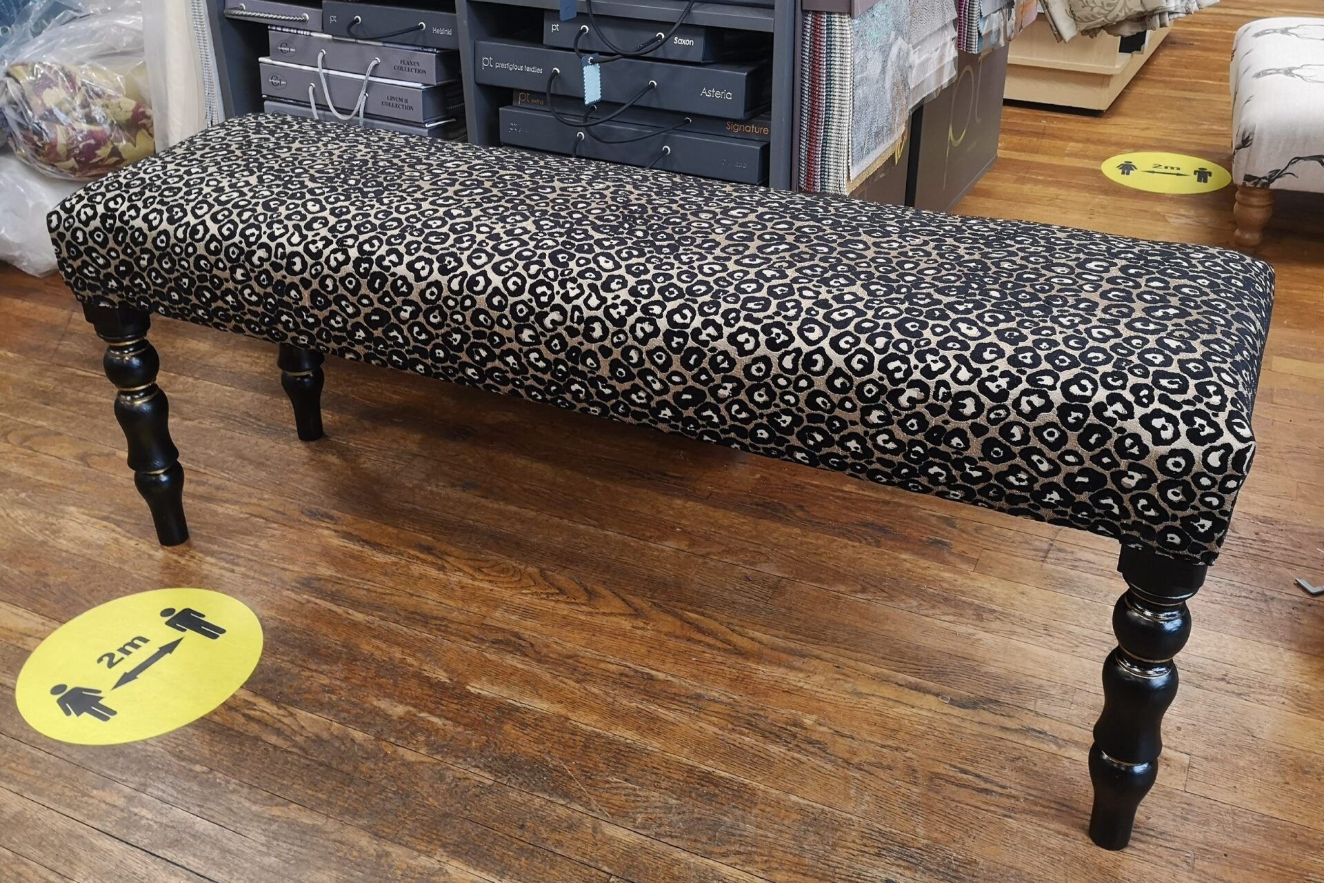 A leopard print bench is sitting on a wooden floor in a store.