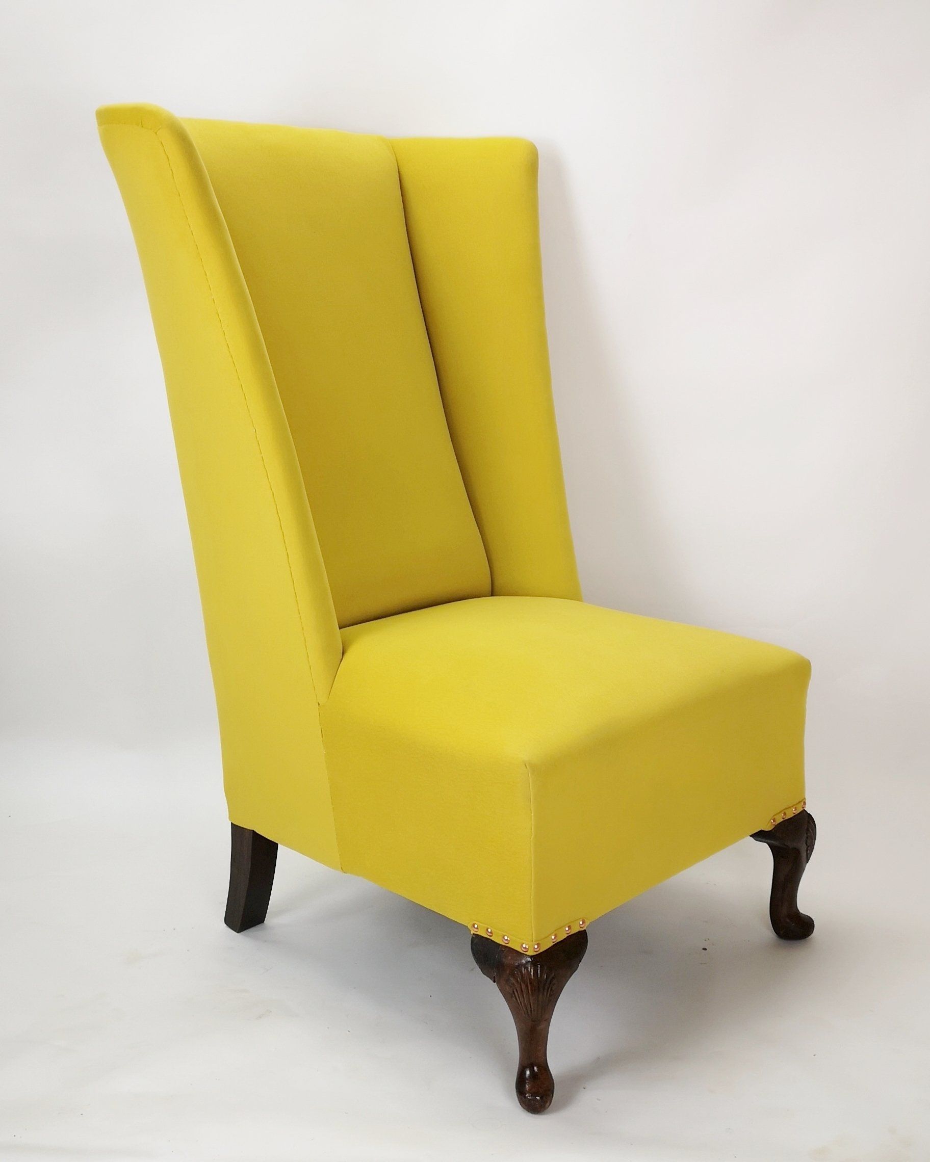 A yellow chair with wooden legs is sitting on a white surface