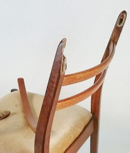 The back of a wooden chair with a broken arm rest