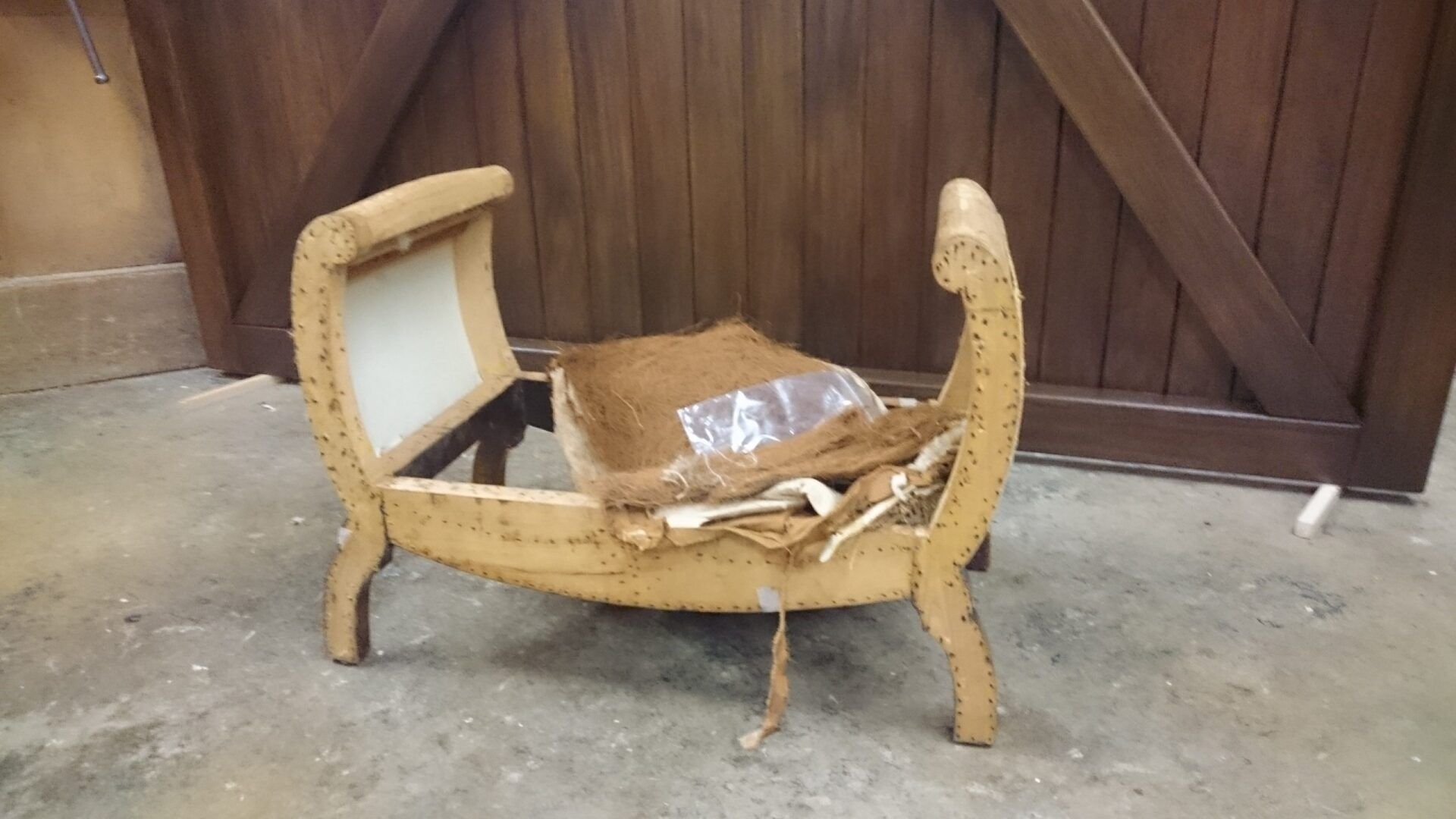 A wooden bench is sitting on the floor in front of a wooden door.