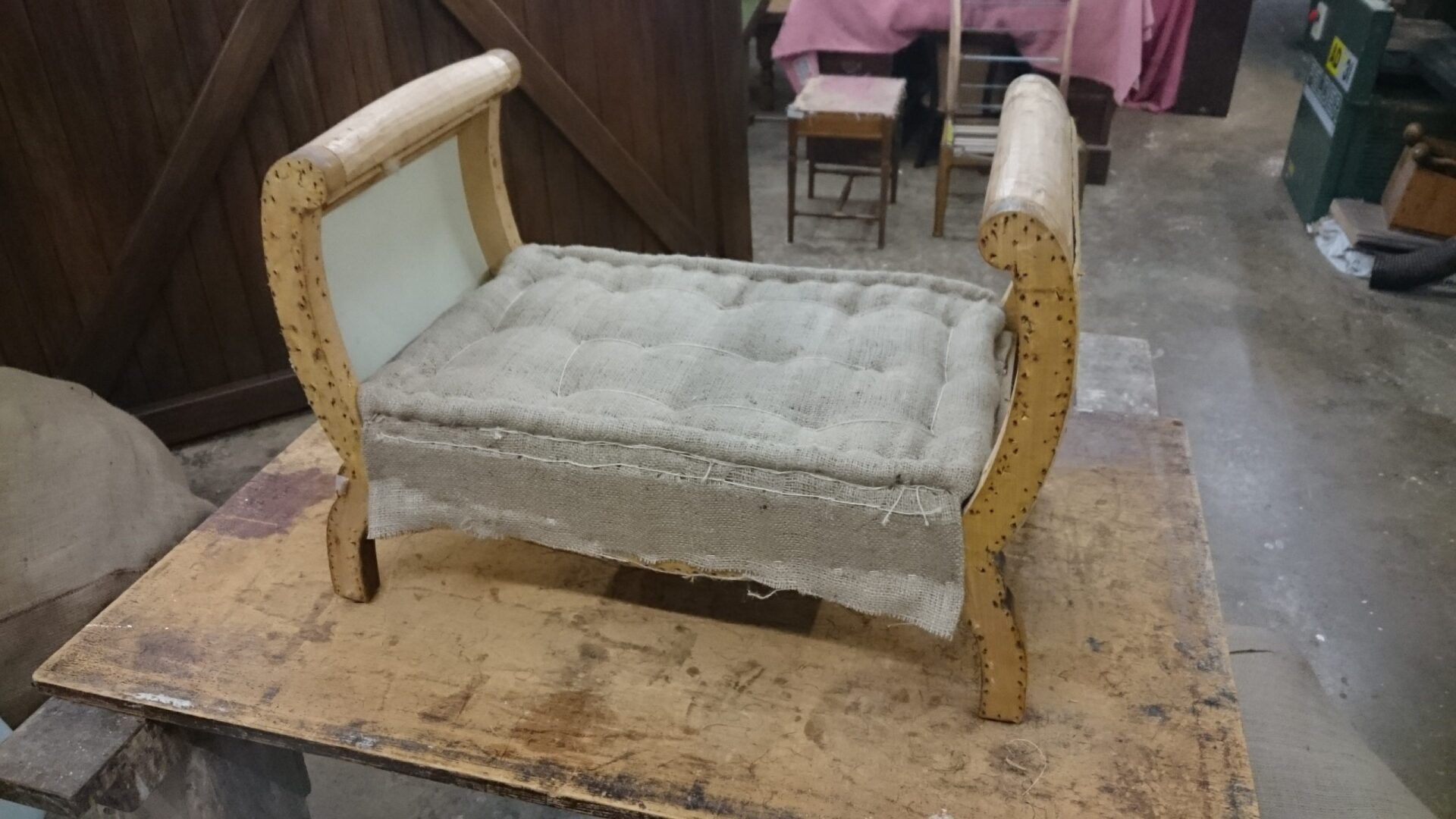 A wooden bench with a white cushion is sitting on a wooden table.