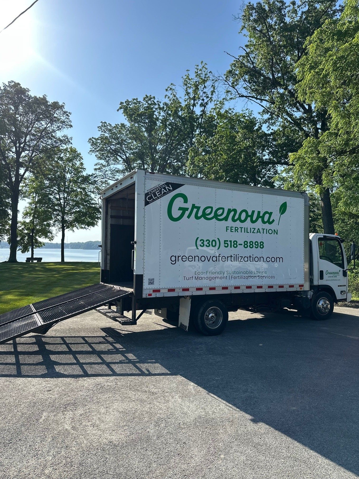 Two children running through a lawn sprinkler on a sunny day. Green grass, blue sky.