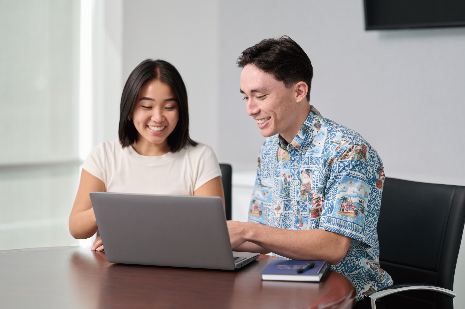 a man and woman working together on a laptop to conduct a business audit in a beautiful conference room.