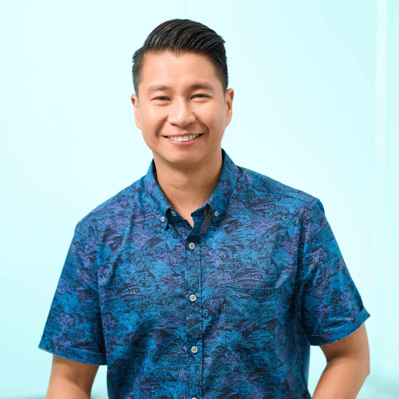 Oahu accounting firm principal John Paul Bautista stands in a conference room wearing a dark blue patterned shirt and a watch.