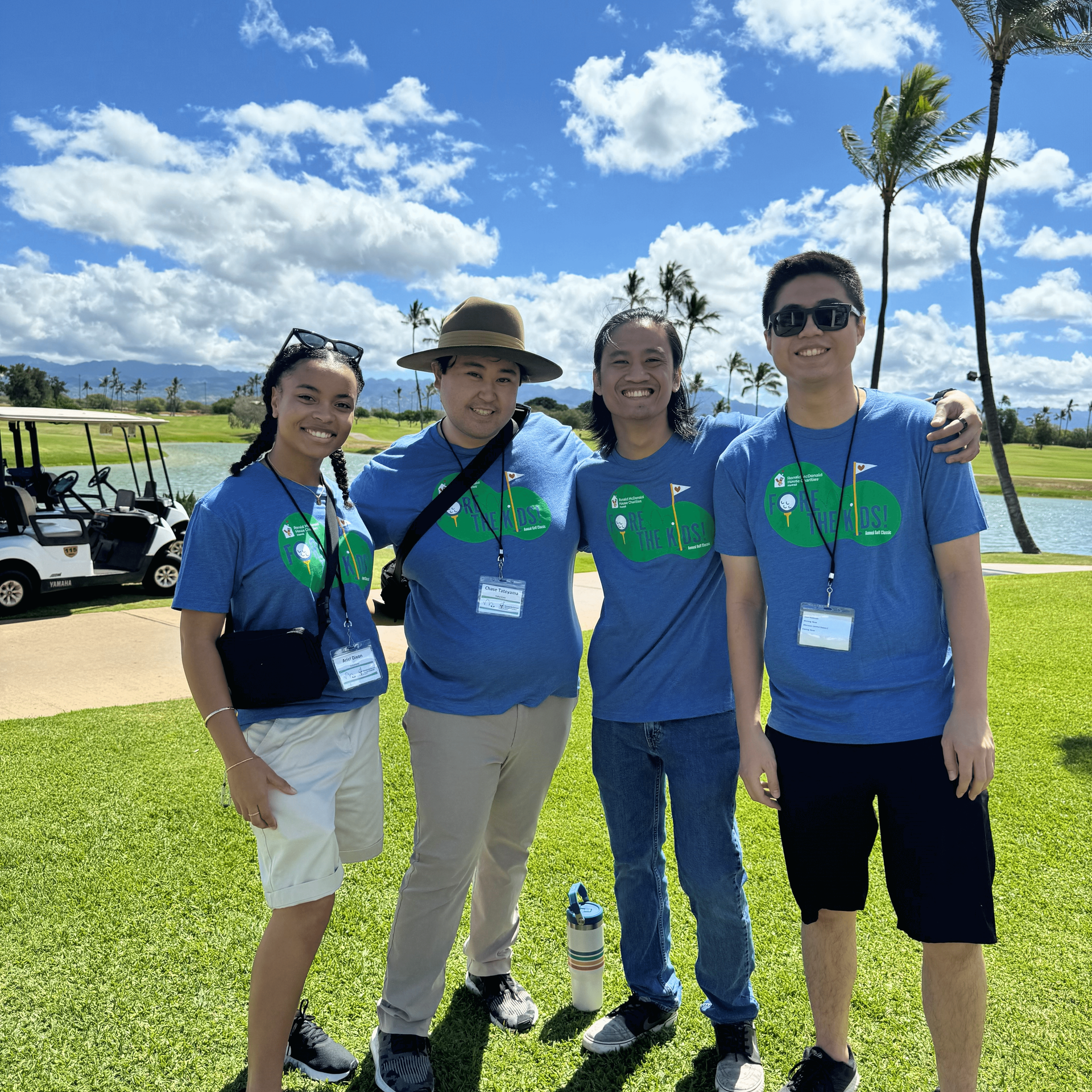 a group of entry-level accountants stand together smiling on a beautiful green golf course for a company incentive event