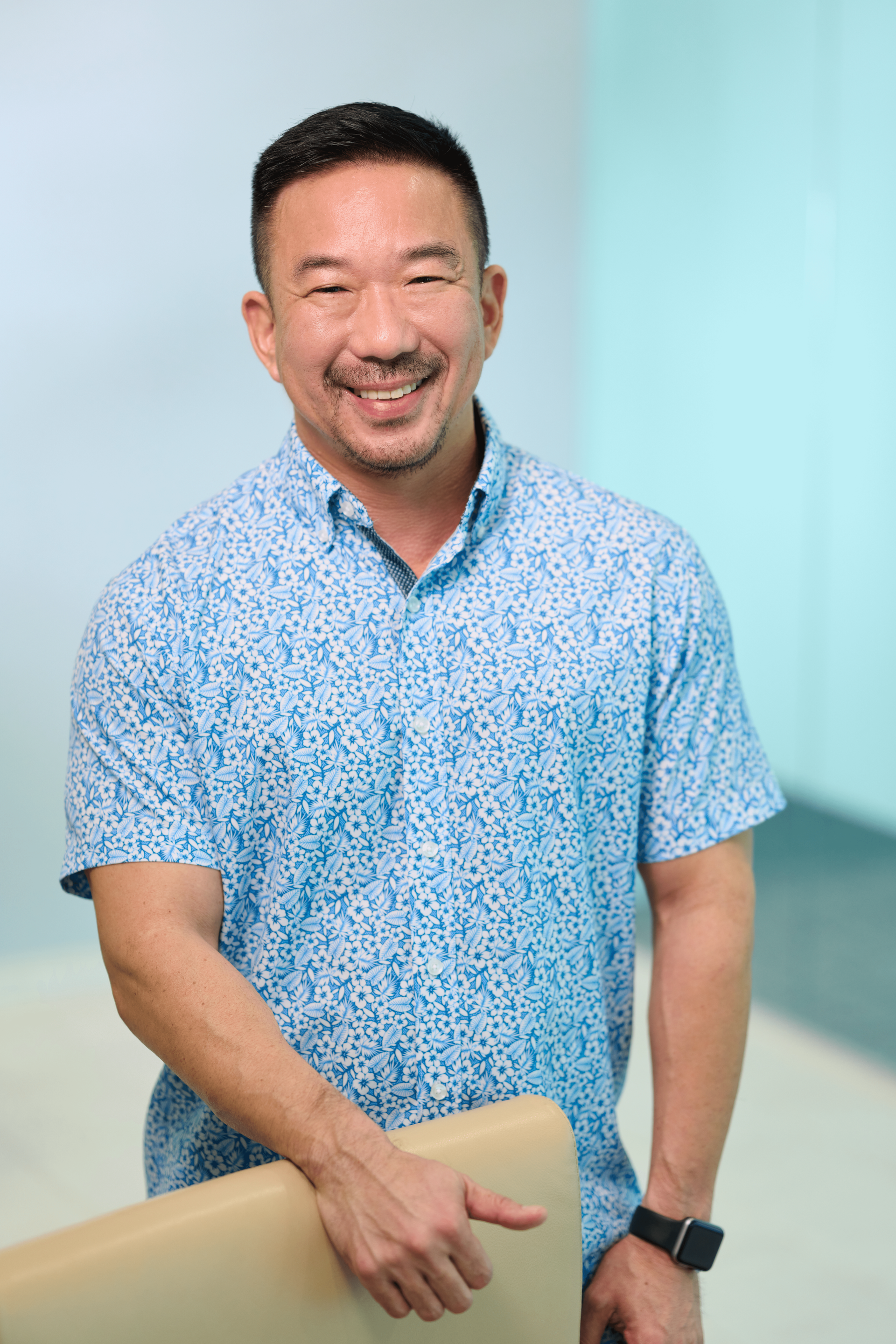 Dwayne S. Takeno, Audit Principal and Audit Division Leader of N&K tax compliance and accounting firm, wearing a light blue aloha shirt and smiling at the camera.