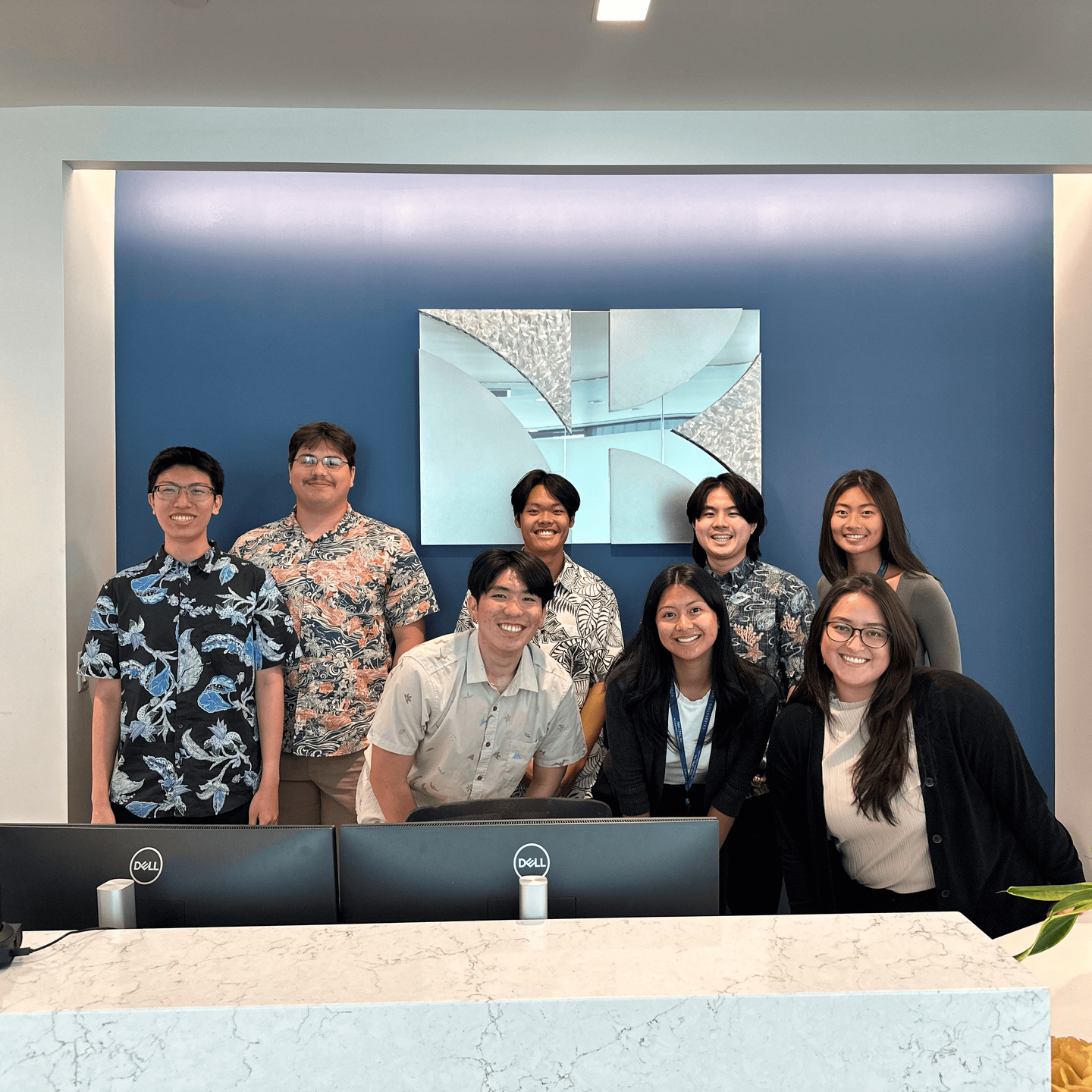 a group of accountant interns stand smiling at the front desk of oahu cpa firm n&k cpas, inc. in Honolulu, hawaii