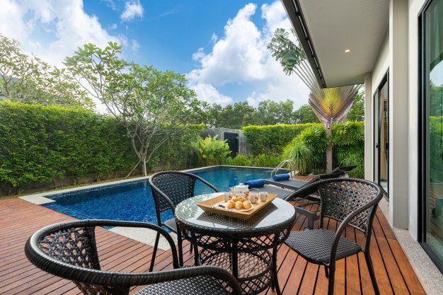 A patio with a table and chairs next to a swimming pool.