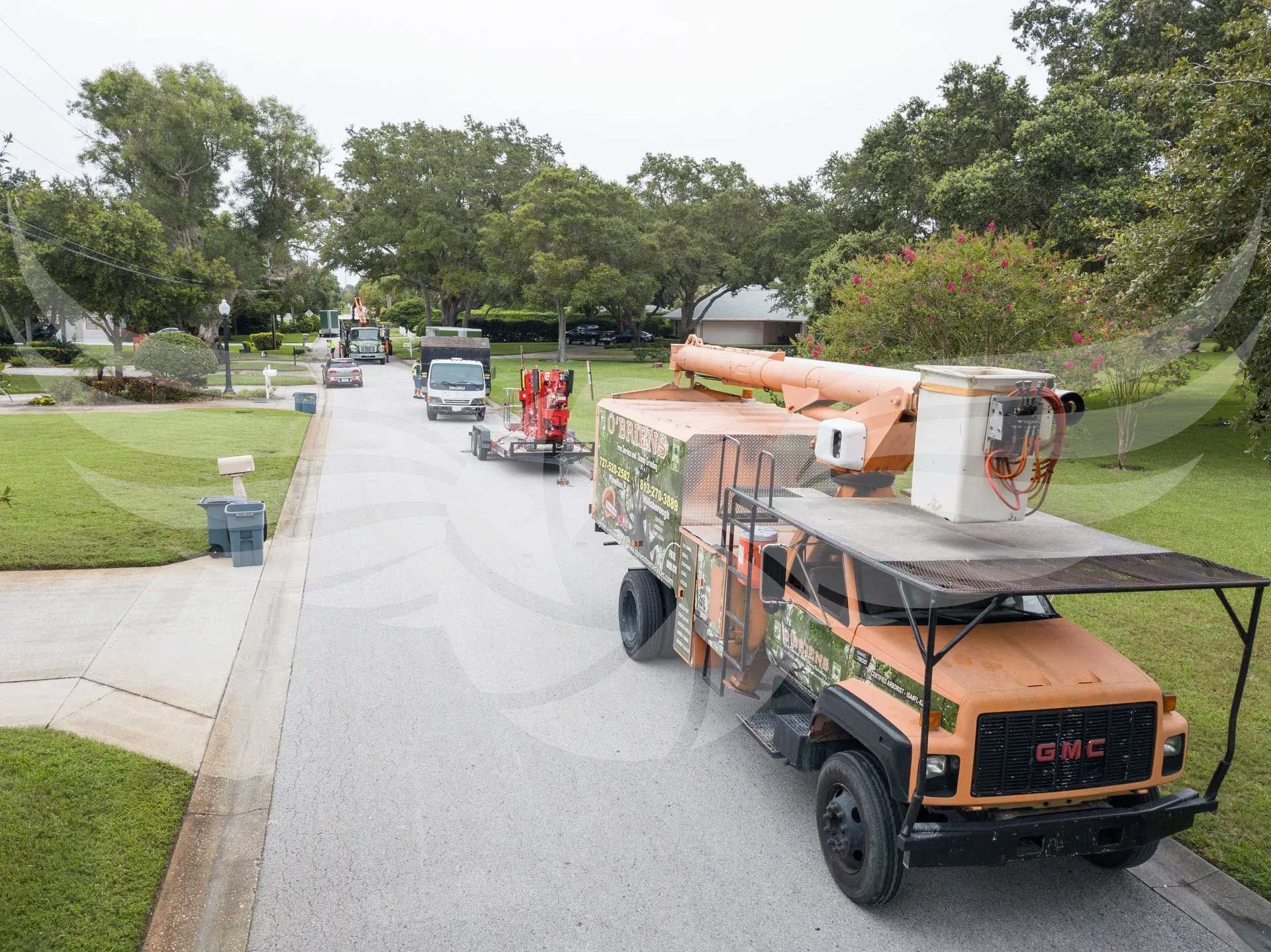 A gmc truck is driving down a street next to a house.