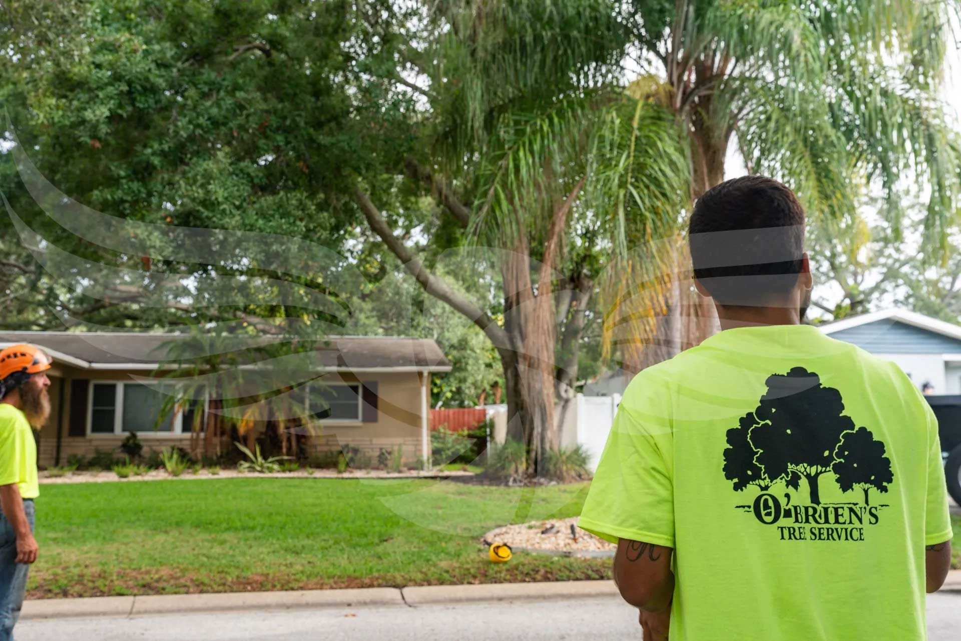 Two men in neon green shirts are standing in front of a house.