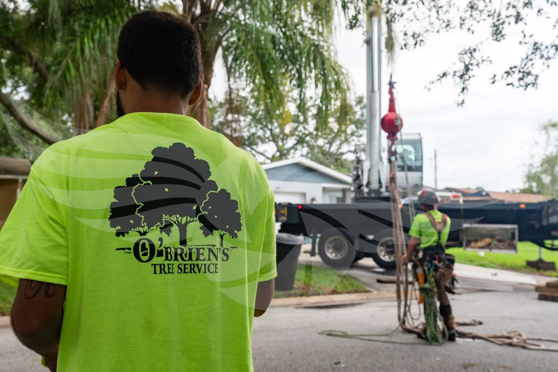 A man in a neon green shirt is standing in front of a crane.