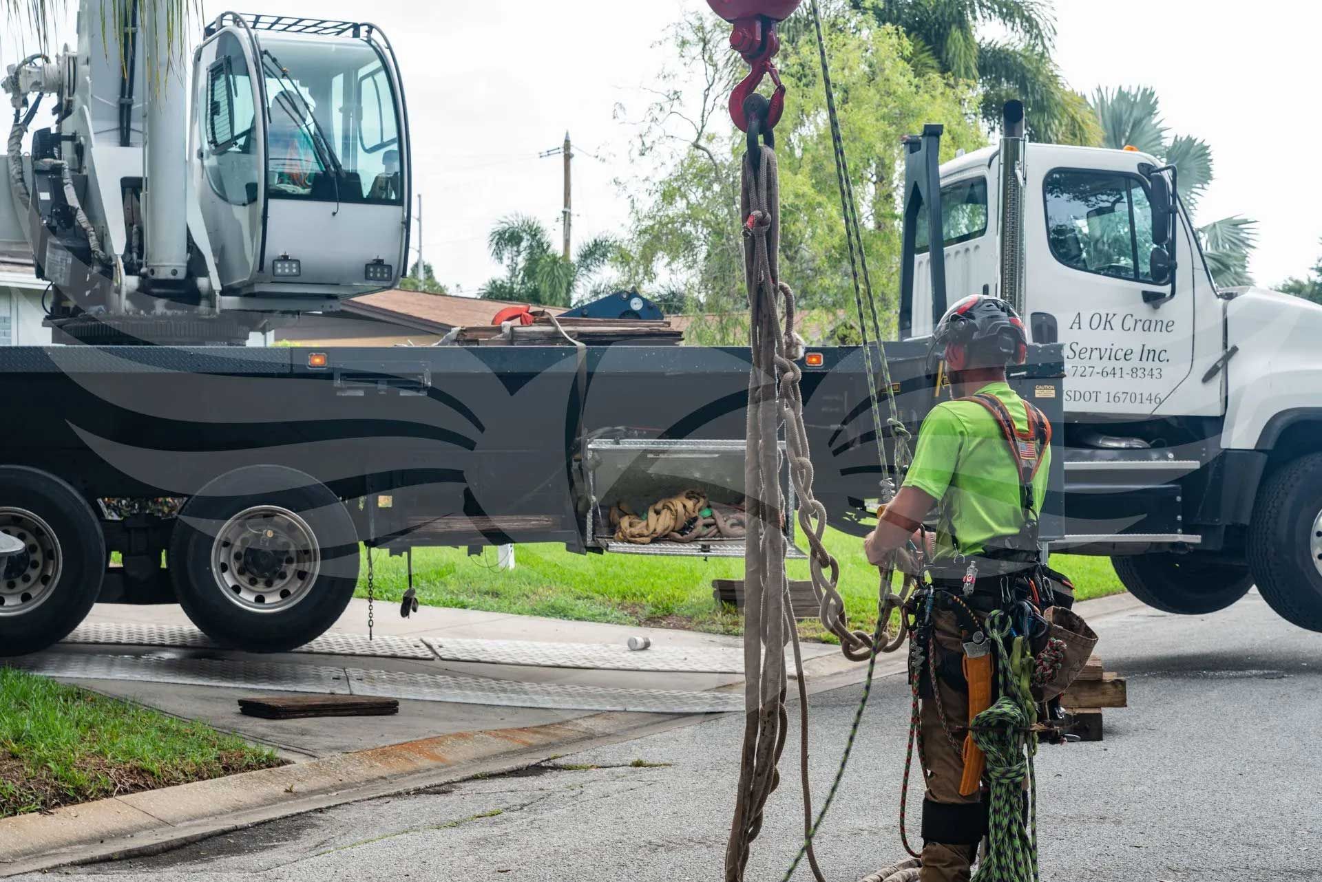 A man is standing in front of a truck with a crane attached to it.