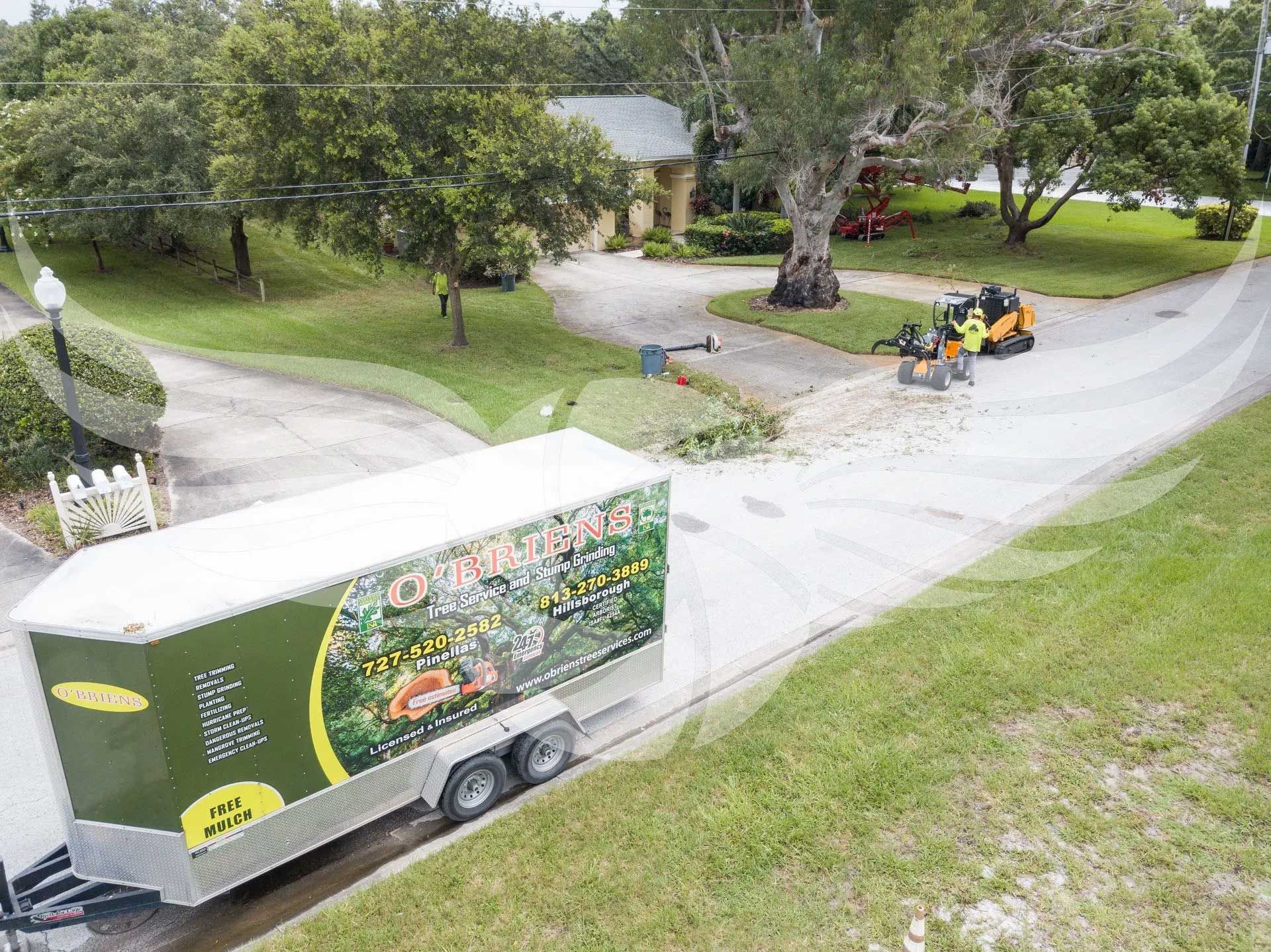 An aerial view of a trailer driving down a road next to a house.