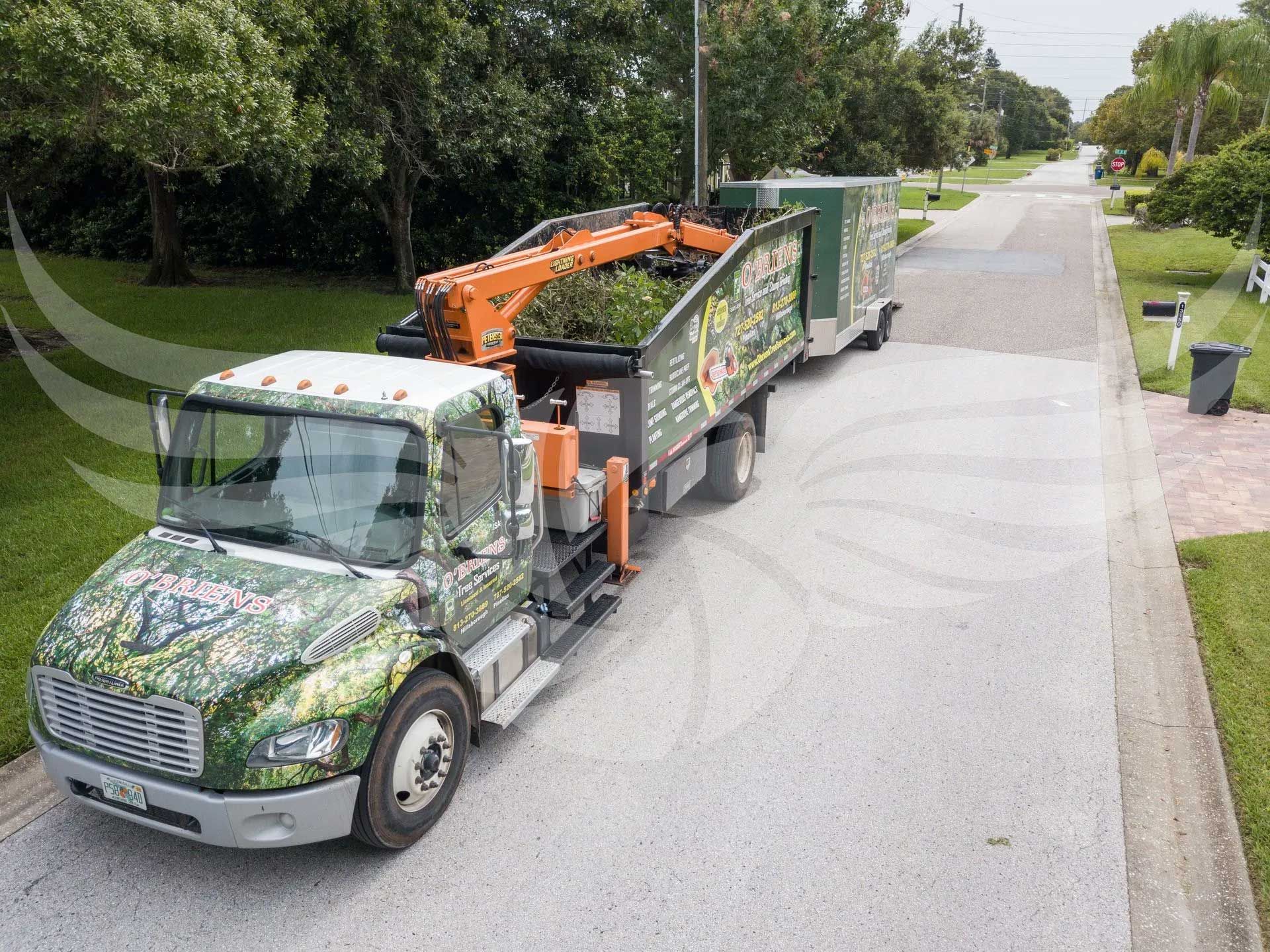 A truck with a crane on the back is driving down a street.