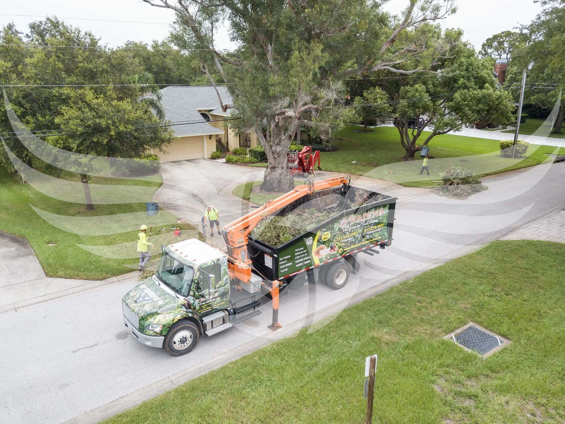 An aerial view of a truck carrying a tree chipper down a street.