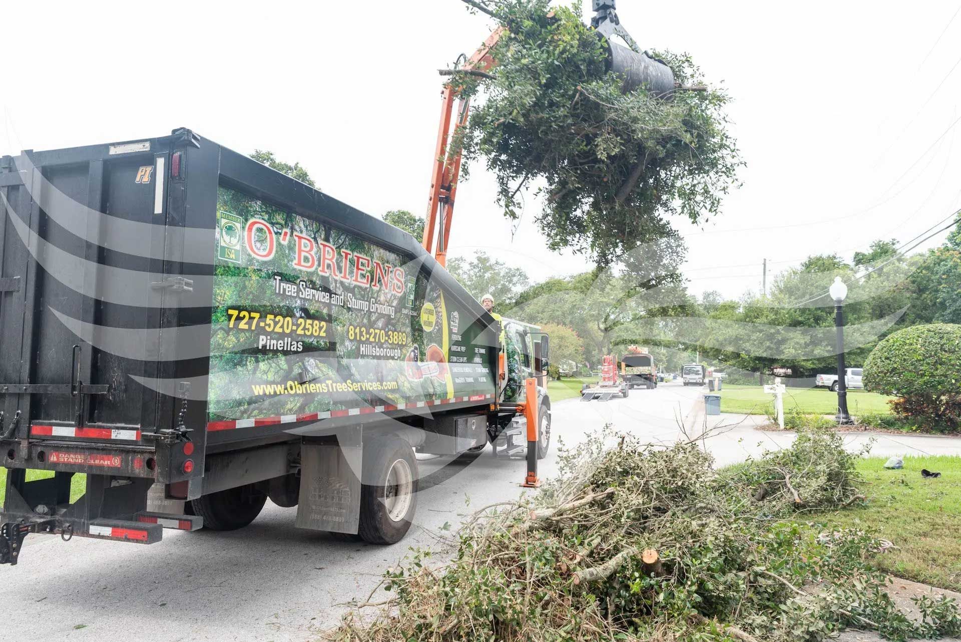 A dump truck with a crane attached to it is driving down a street.