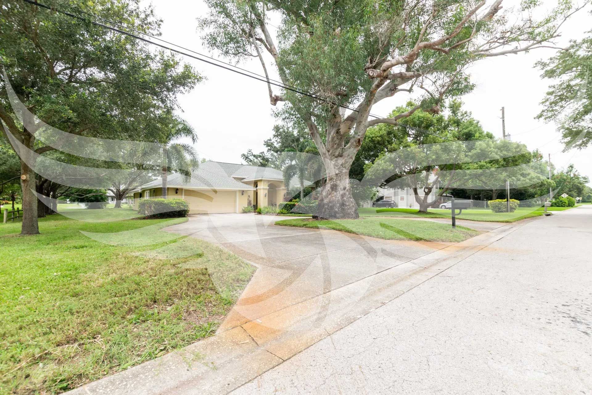 A house is sitting on the corner of a street next to a tree.