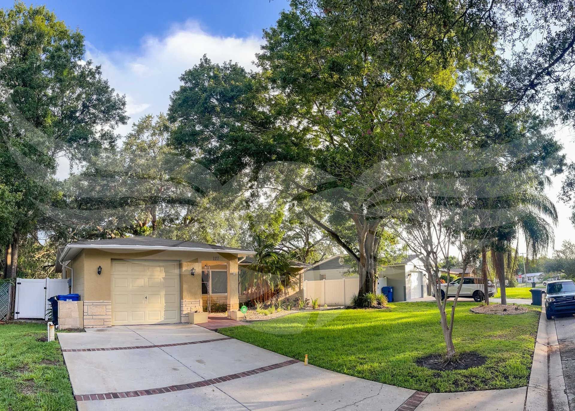 A house with a garage and a driveway surrounded by trees