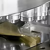Close-up of a machine pressing material with several cylindrical parts.