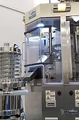 Pharmaceutical packaging machine with clear protective enclosure, silver metal, and warning labels.