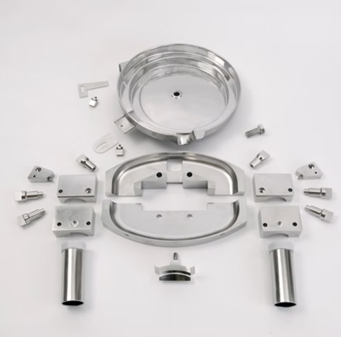 Exploded view of stainless steel mechanical parts, including a circular container, blocks, and fasteners.