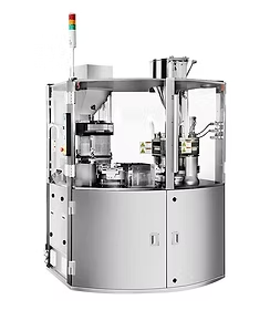 Pharmaceutical capsule filling machine in a clean, industrial setting with a clear protective enclosure.