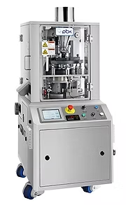 Tablet pressing machine, gray metal with control panel, in a laboratory setting.