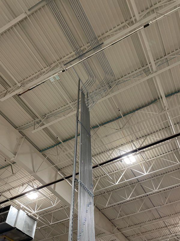 The ceiling of a large building with a lot of wires hanging from it.