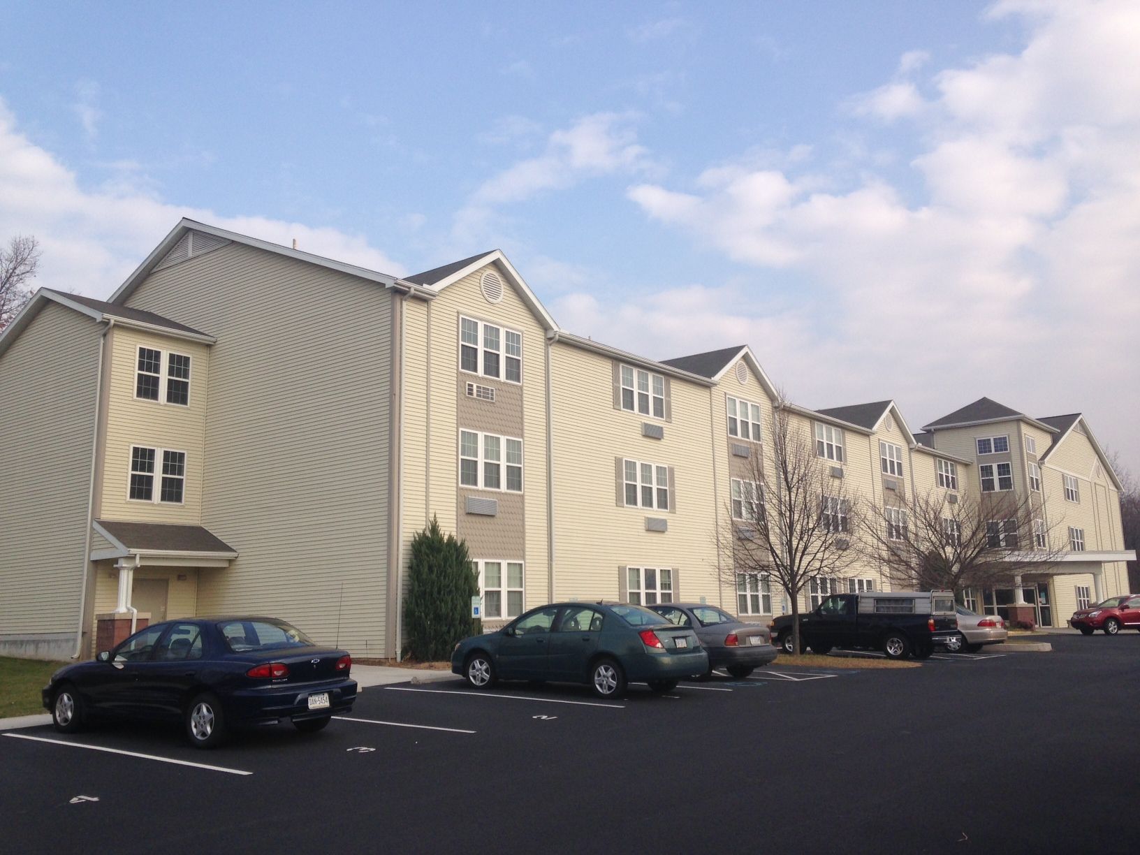 Several cars are parked in front of a large apartment building
