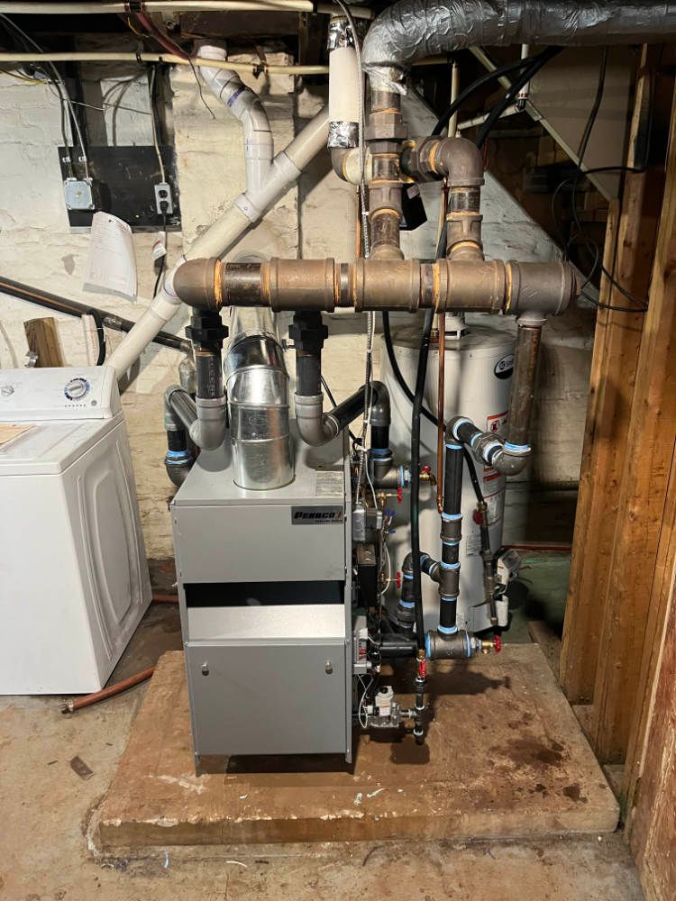 A boiler is sitting in a basement next to a washer and dryer.