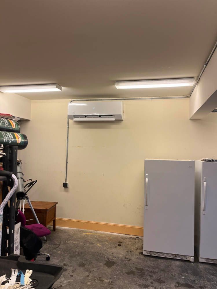 A room with two refrigerators and an air conditioner on the wall.