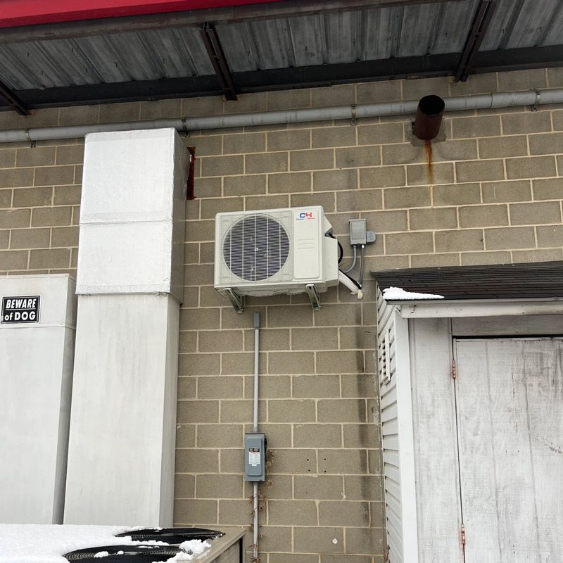 A white house with a stainless steel air conditioner on the side of it.