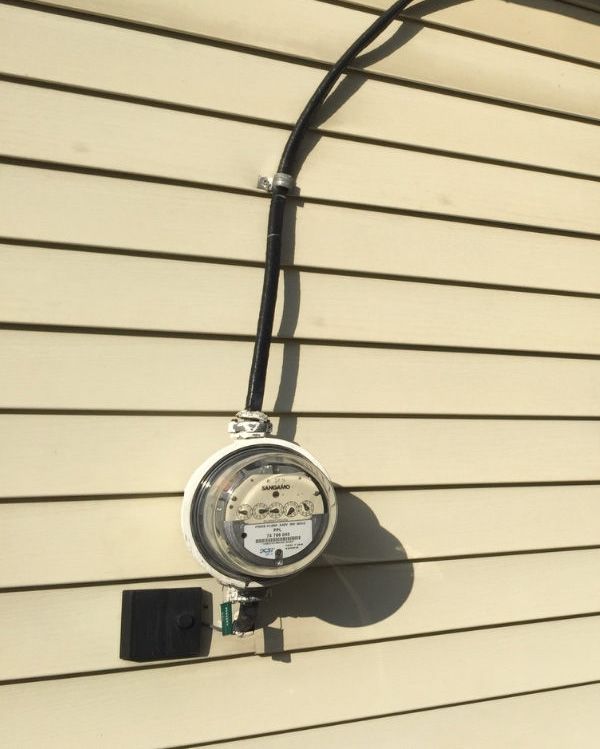 An electric meter is attached to the side of a house