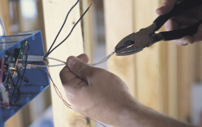 A person is cutting a wire with a pair of pliers.