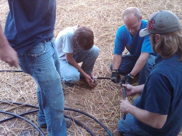 A man wearing a ny hat is working on a hose
