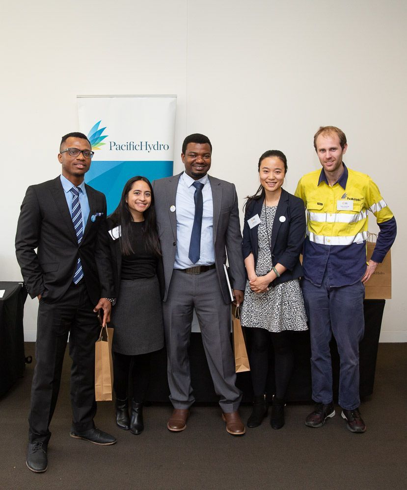 A group of people standing next to each other in front of a sign that says pacific hydro