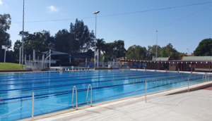 A large swimming pool surrounded by trees on a sunny day.