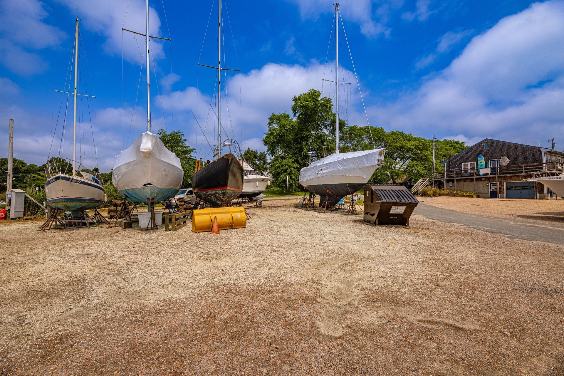 A group of boats are sitting on top of a dirt field.