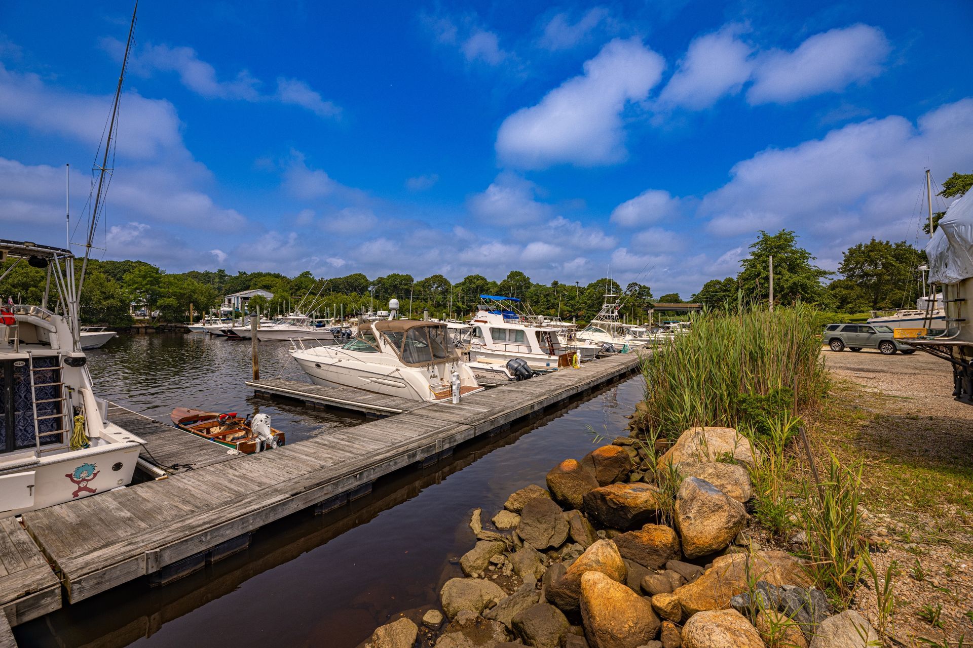 A dock filled with boats on a river on a sunny day.